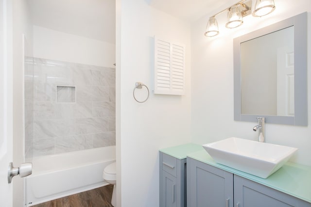 full bathroom with vanity, tiled shower / bath, hardwood / wood-style flooring, and toilet