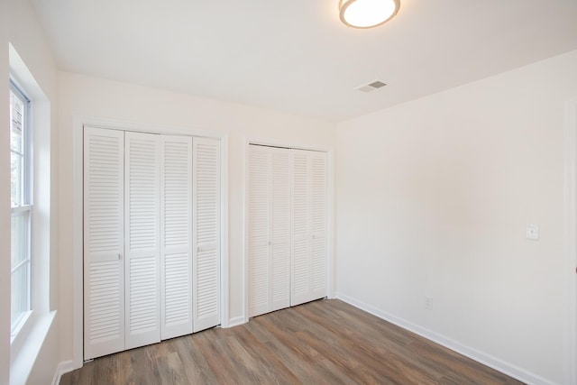 unfurnished bedroom featuring multiple closets and hardwood / wood-style floors