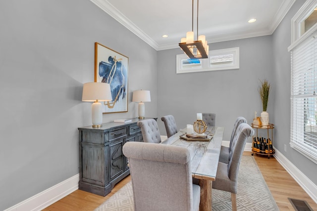 dining area with ornamental molding and light hardwood / wood-style flooring