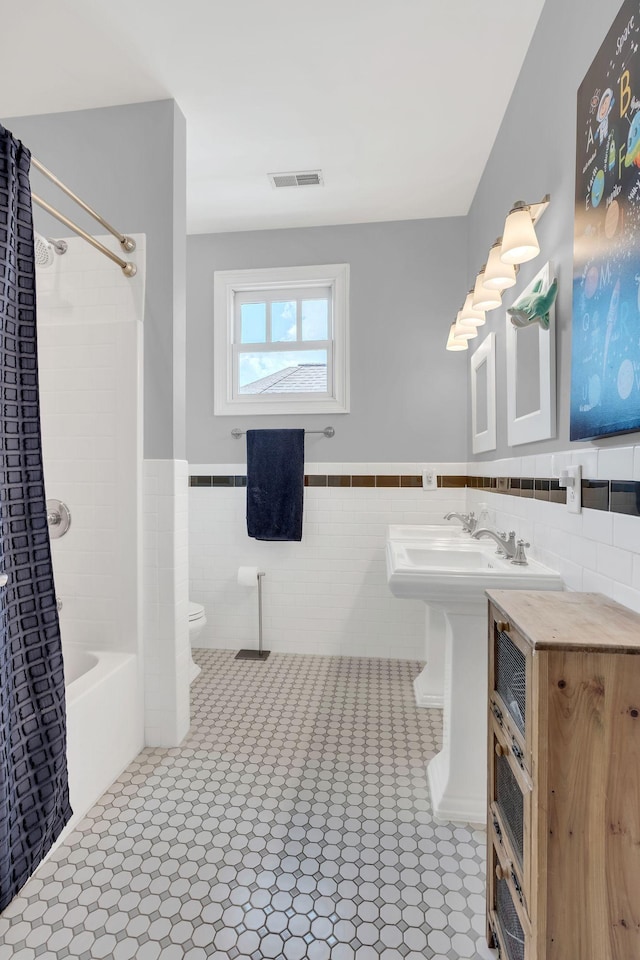 bathroom featuring tile walls, shower / bath combo, tile patterned floors, and toilet