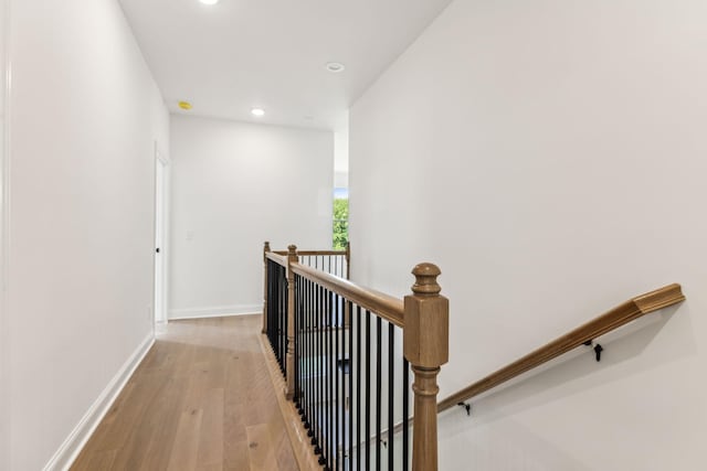 hallway featuring recessed lighting, baseboards, light wood finished floors, and an upstairs landing