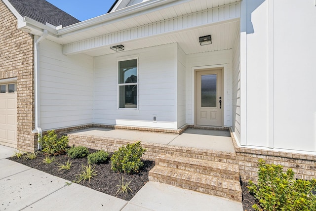 doorway to property featuring an attached garage, a shingled roof, a porch, and brick siding