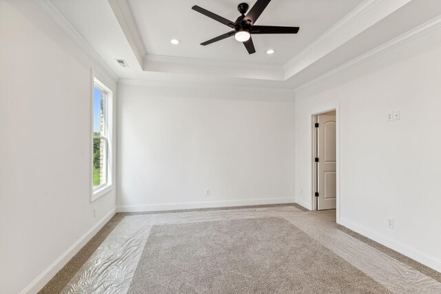 carpeted empty room with ceiling fan, crown molding, and a tray ceiling