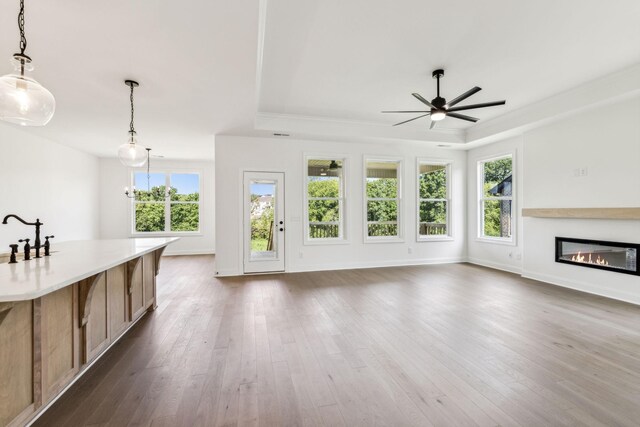 unfurnished living room with ceiling fan, wood-type flooring, and a raised ceiling