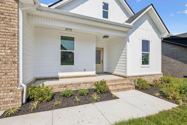 property entrance featuring board and batten siding, covered porch, and brick siding