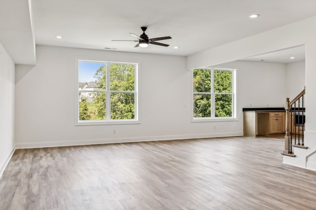 unfurnished living room with light hardwood / wood-style flooring, a healthy amount of sunlight, and ceiling fan