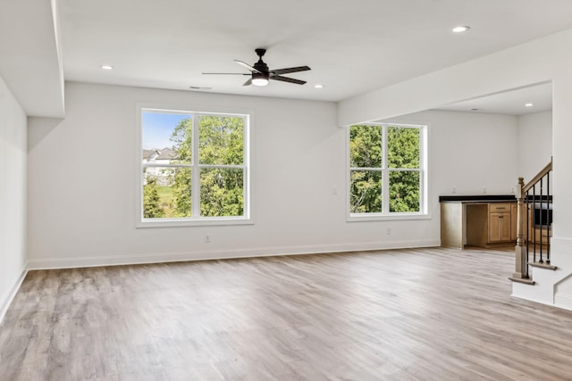 unfurnished living room with a healthy amount of sunlight, light wood-style floors, stairway, and recessed lighting