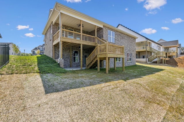 back of property with a lawn, a ceiling fan, stairs, a wooden deck, and brick siding