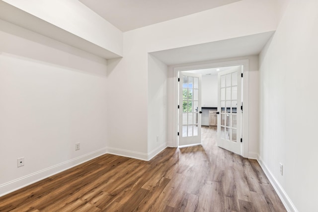 spare room featuring baseboards, wood finished floors, and french doors