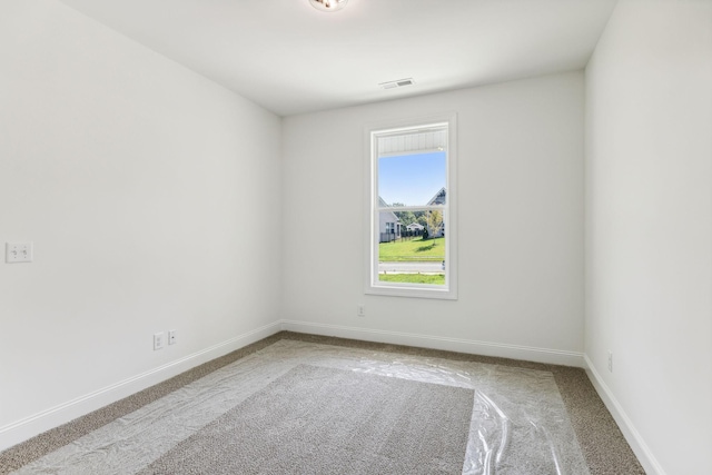 carpeted spare room with visible vents and baseboards