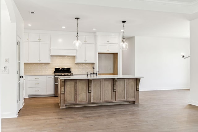 kitchen with double oven range, light wood-style flooring, backsplash, and light countertops