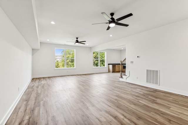 unfurnished living room featuring baseboards, visible vents, wood finished floors, stairs, and recessed lighting