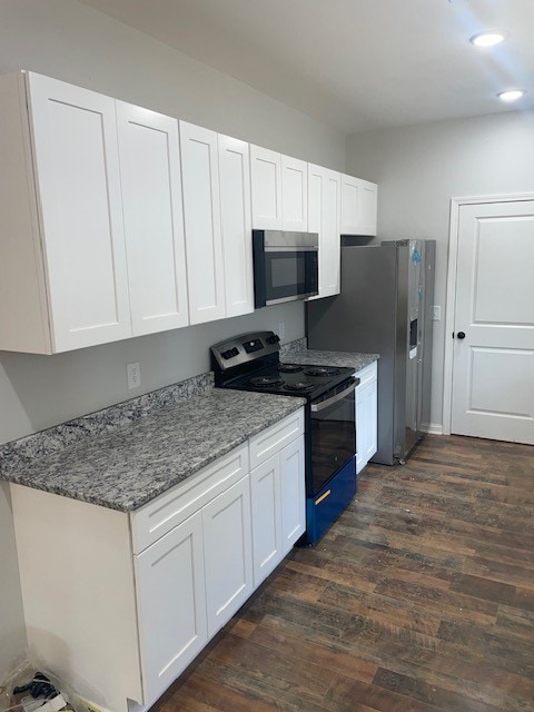 kitchen with white cabinetry, dark hardwood / wood-style flooring, black appliances, and light stone counters