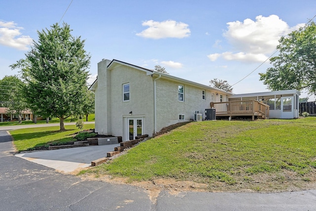 view of property exterior with a wooden deck, a yard, and central AC