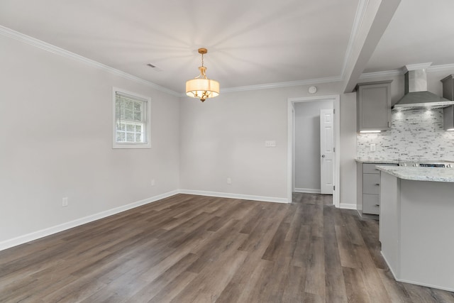 interior space with gray cabinets, decorative light fixtures, wall chimney range hood, hardwood / wood-style floors, and backsplash