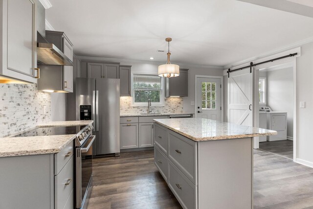 kitchen with dark wood-type flooring, a barn door, stainless steel appliances, decorative backsplash, and gray cabinetry