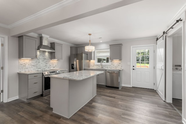 kitchen featuring tasteful backsplash, wall chimney range hood, stainless steel appliances, a barn door, and a center island