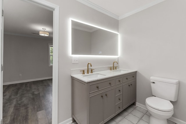 bathroom featuring toilet, hardwood / wood-style flooring, dual bowl vanity, and crown molding