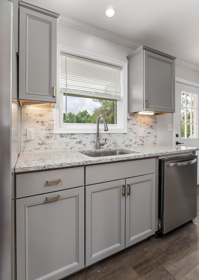 kitchen with dark hardwood / wood-style flooring, sink, dishwasher, light stone counters, and backsplash