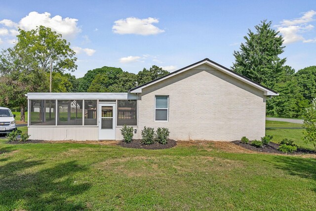 rear view of property featuring a sunroom and a yard