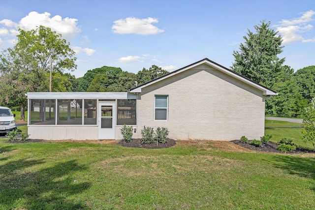 rear view of property featuring a sunroom and a lawn