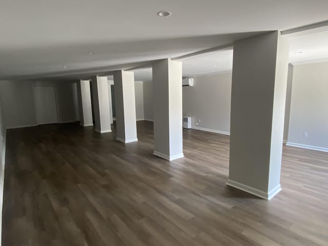 basement featuring a wall mounted air conditioner and dark hardwood / wood-style flooring