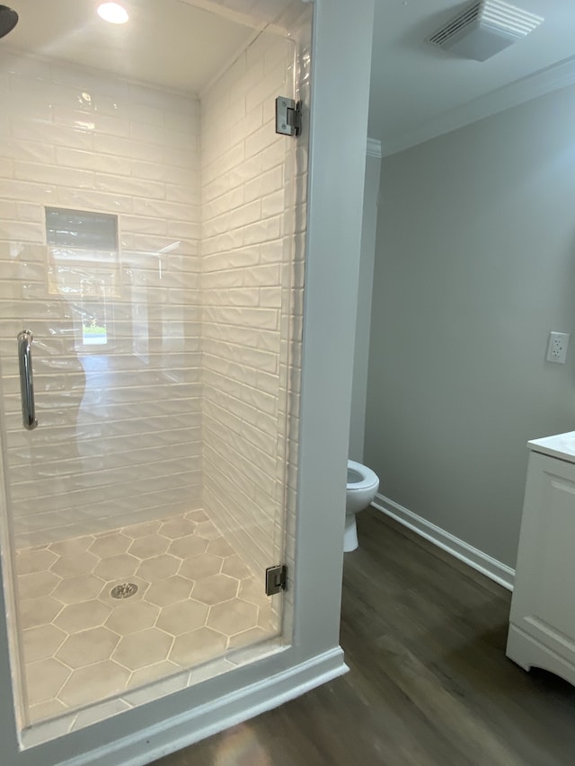 bathroom featuring walk in shower, hardwood / wood-style floors, toilet, and ornamental molding