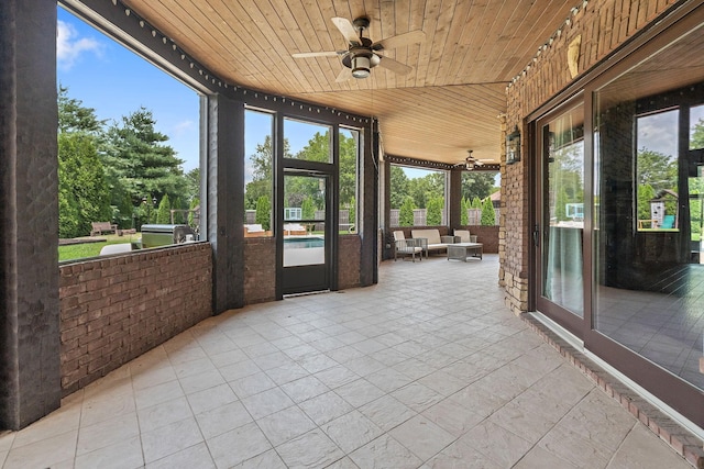 unfurnished sunroom featuring wooden ceiling and ceiling fan