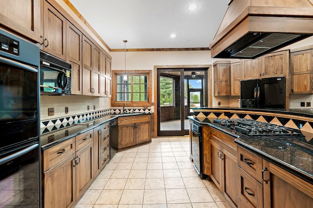 kitchen featuring black appliances, decorative backsplash, decorative light fixtures, custom exhaust hood, and dark stone counters