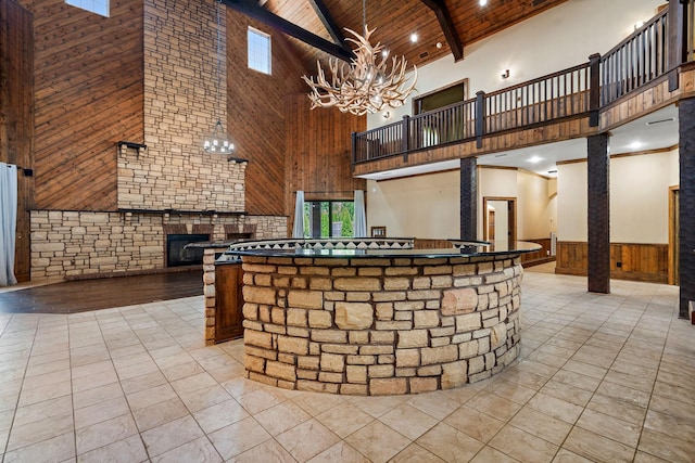 kitchen featuring wooden walls, beamed ceiling, a healthy amount of sunlight, wooden ceiling, and an inviting chandelier