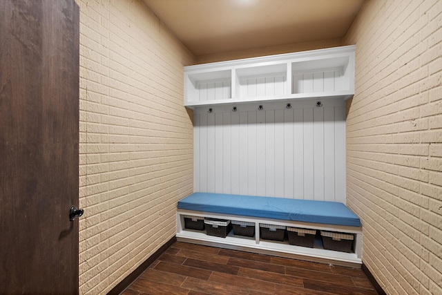 mudroom with brick wall and dark hardwood / wood-style flooring