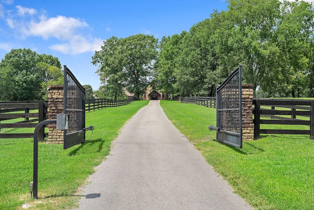 view of gate featuring a rural view and a lawn