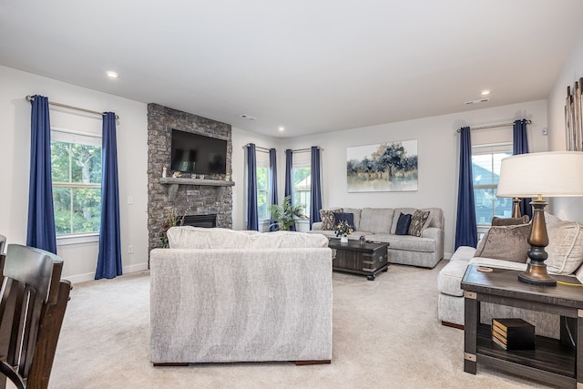 carpeted living room featuring a stone fireplace and a healthy amount of sunlight