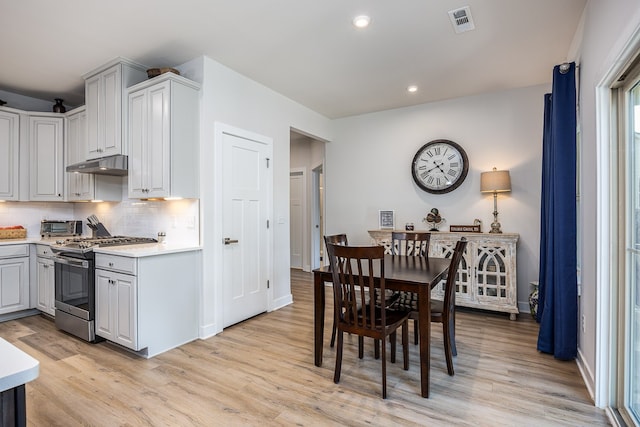 kitchen featuring decorative backsplash, gas stove, light hardwood / wood-style floors, and gray cabinetry