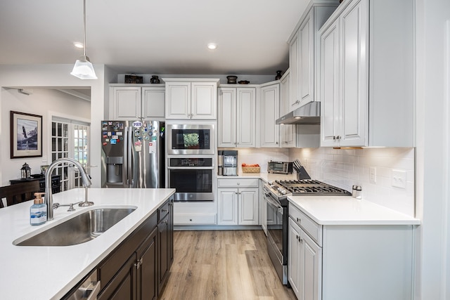 kitchen with sink, appliances with stainless steel finishes, white cabinets, and light hardwood / wood-style floors