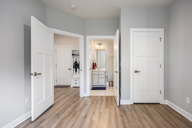 unfurnished bedroom with sink, connected bathroom, and light hardwood / wood-style floors