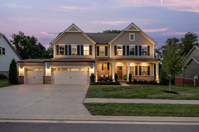 craftsman house with a garage, a porch, and a lawn