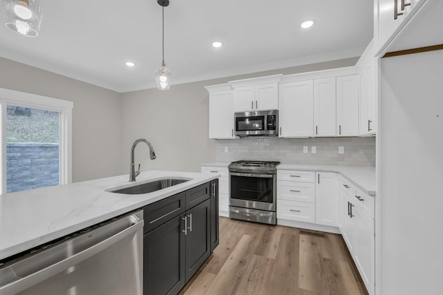 kitchen with sink, crown molding, appliances with stainless steel finishes, white cabinetry, and hanging light fixtures