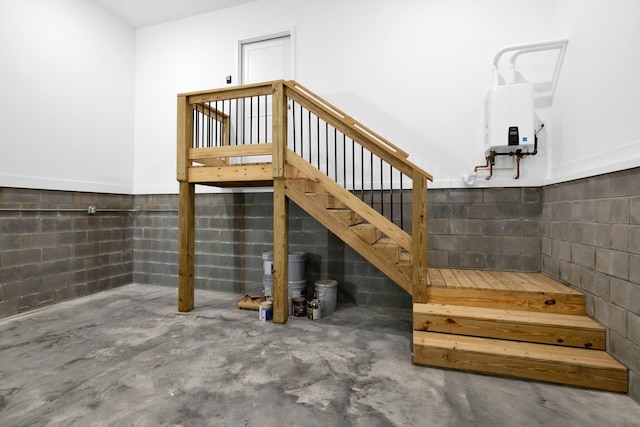 stairs with concrete flooring and water heater