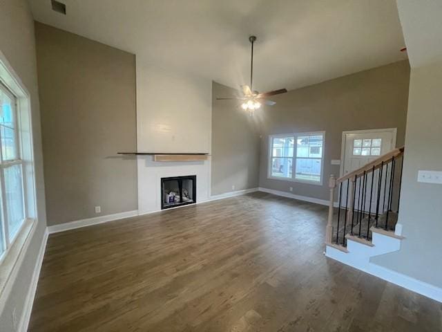 unfurnished living room featuring ceiling fan, plenty of natural light, dark wood-type flooring, and vaulted ceiling