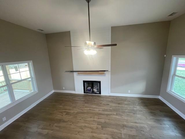 unfurnished living room with dark hardwood / wood-style floors and ceiling fan