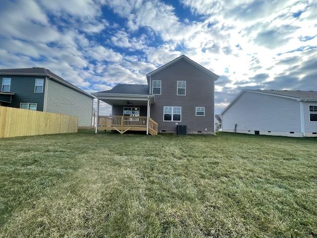 rear view of house with central AC, a wooden deck, and a lawn