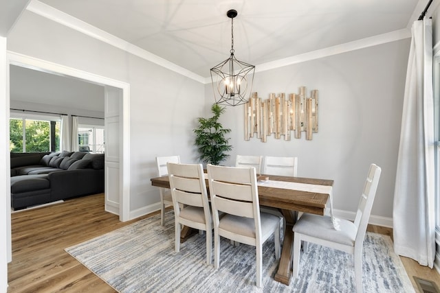 dining space featuring a notable chandelier, light wood-type flooring, and crown molding