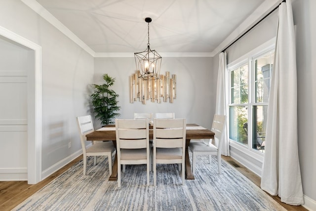 dining space featuring wood-type flooring, a healthy amount of sunlight, ornamental molding, and an inviting chandelier