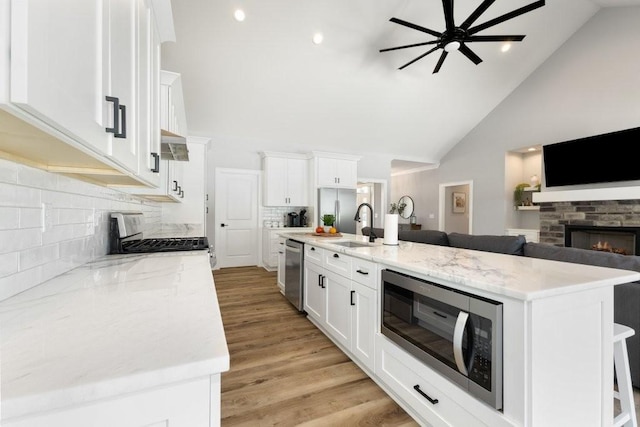 kitchen with a kitchen bar, stainless steel appliances, white cabinets, and a center island with sink