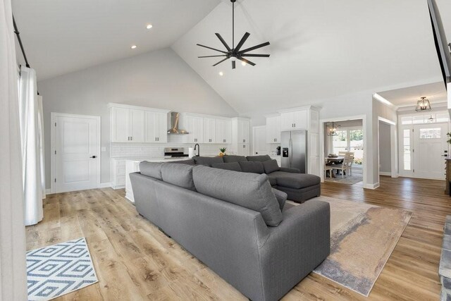 living room featuring light hardwood / wood-style flooring, sink, ceiling fan, and high vaulted ceiling