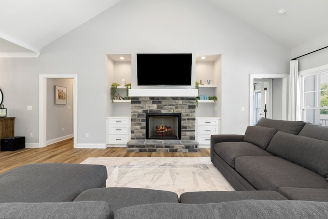 living room featuring light wood-type flooring, high vaulted ceiling, and built in shelves