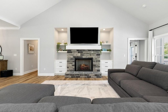 living room featuring high vaulted ceiling, a fireplace, and light hardwood / wood-style floors