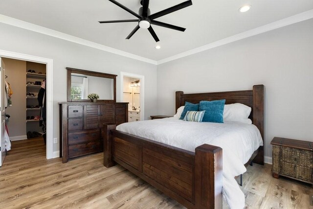 bedroom featuring ensuite bath, light hardwood / wood-style flooring, a walk in closet, and ceiling fan