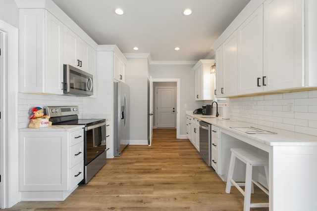 kitchen with white cabinetry, stainless steel appliances, light hardwood / wood-style floors, tasteful backsplash, and sink